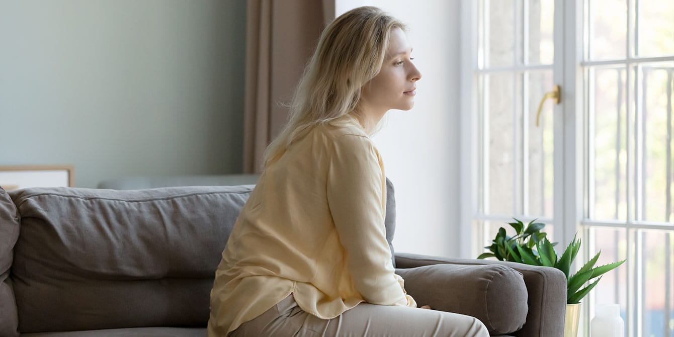 woman dealing with infertility looking out the window looking solemn