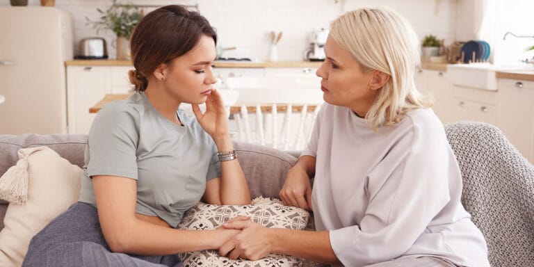 moms sharing secrets sitting on couch