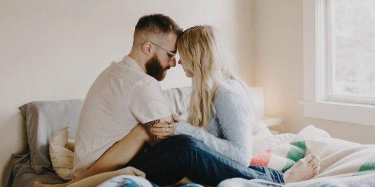 couple holding each other on a bed - men and miscarriage grief