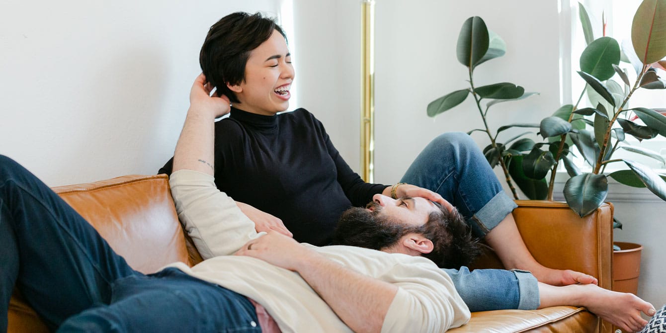 couple laughing on the couch together - how to connect with your spouse