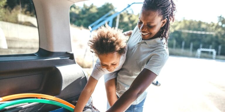 Mom holding son while unpacking minivan