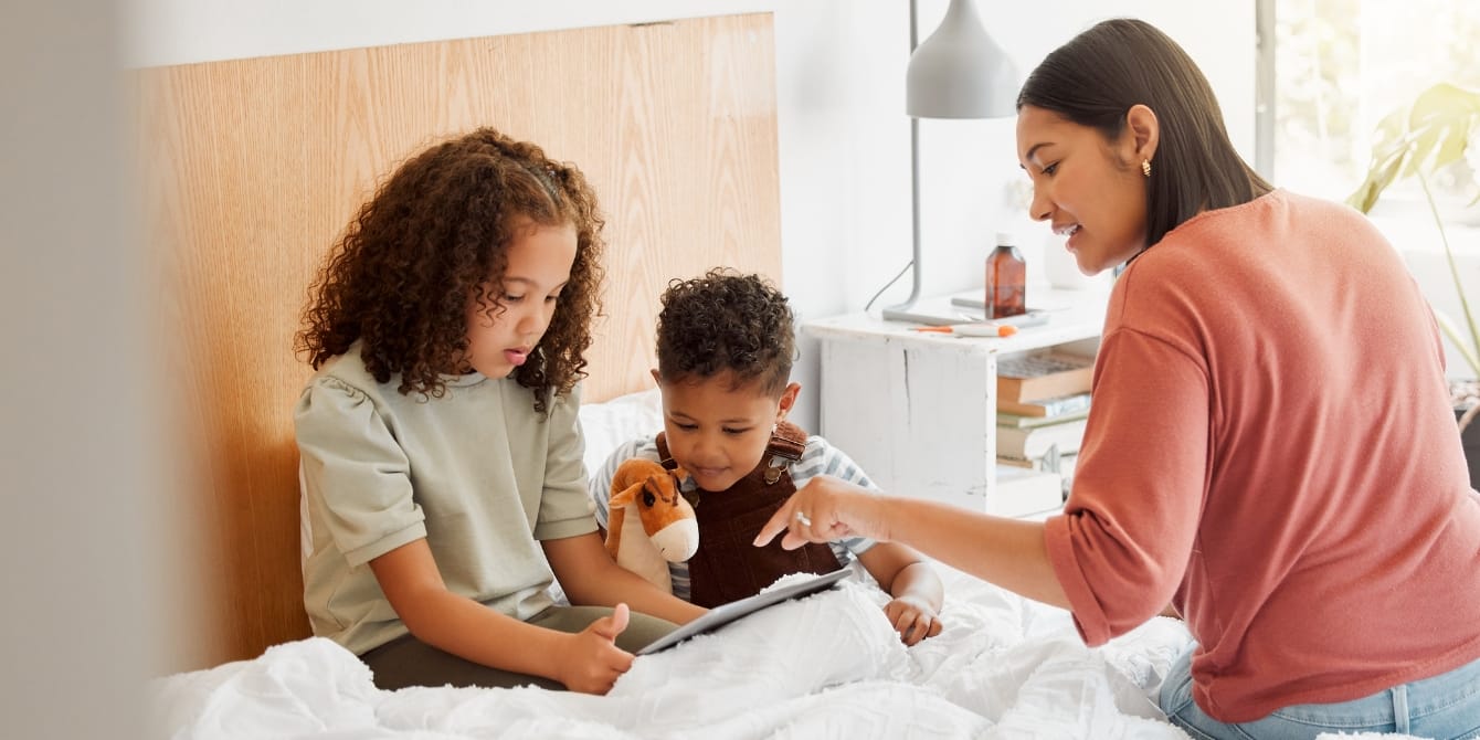 mom sitting with young kids using iPad - how to talk about technology with kids