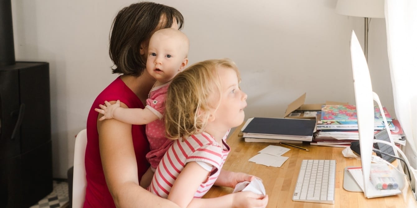 mother trying to work wtih toddler and baby on her lap - women on why they left the workforce