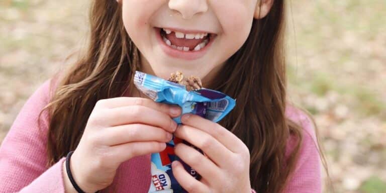 girl holding snack bar- store-bought snacks