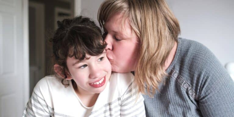 mom kissing daughter spreading awareness on how to help families with autism