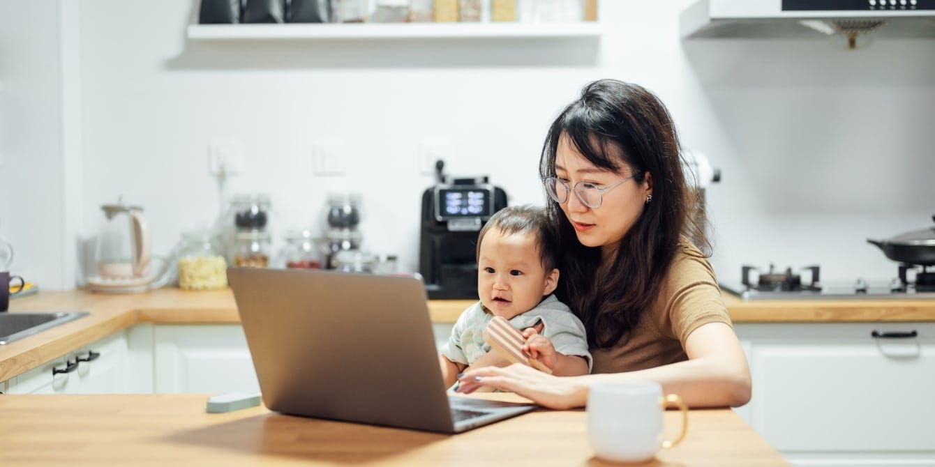 mom working with baby on her lap another reason why parental leave isn't enough for working parents