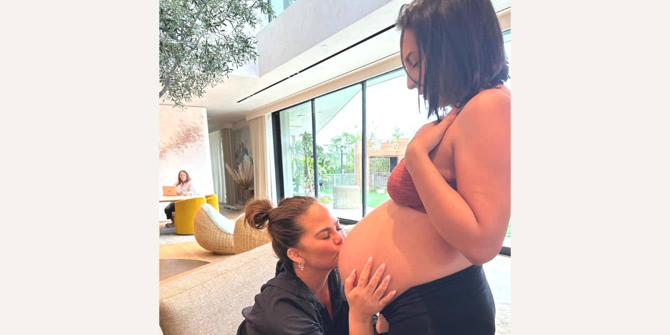 Chrissy Teigen kisses her surrogate's belly