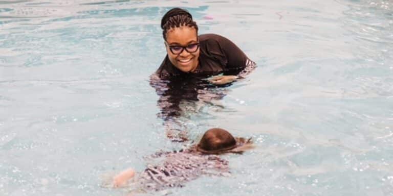 survival swim instructor helps child learn to swim - swim safety