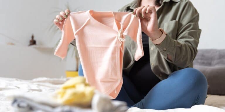 woman holding baby clothes from online thrift store