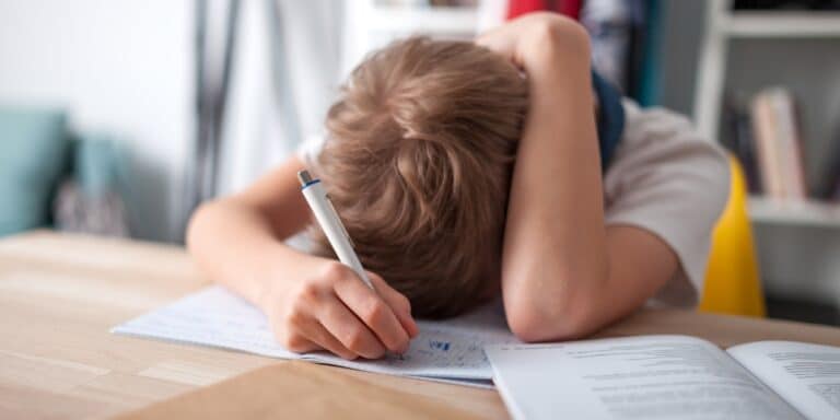 child doing school work with head on table