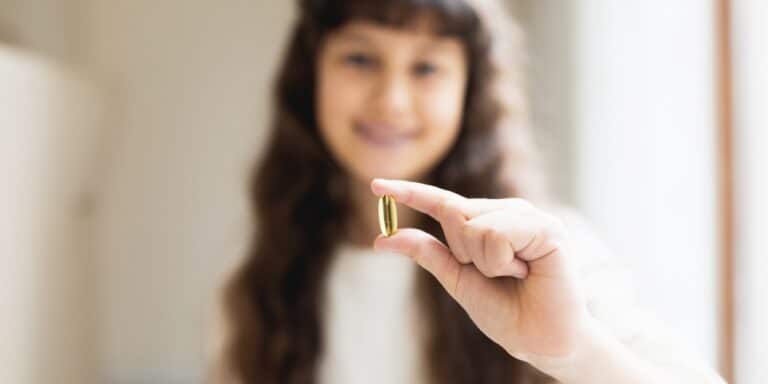 young teen girl holding vitamin - best vitamins for teens