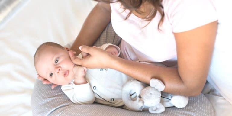 Mom uses nursing pillow with infant