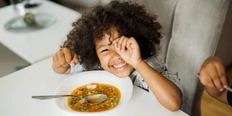 child eating soup at the table- fiber rich foods for kids