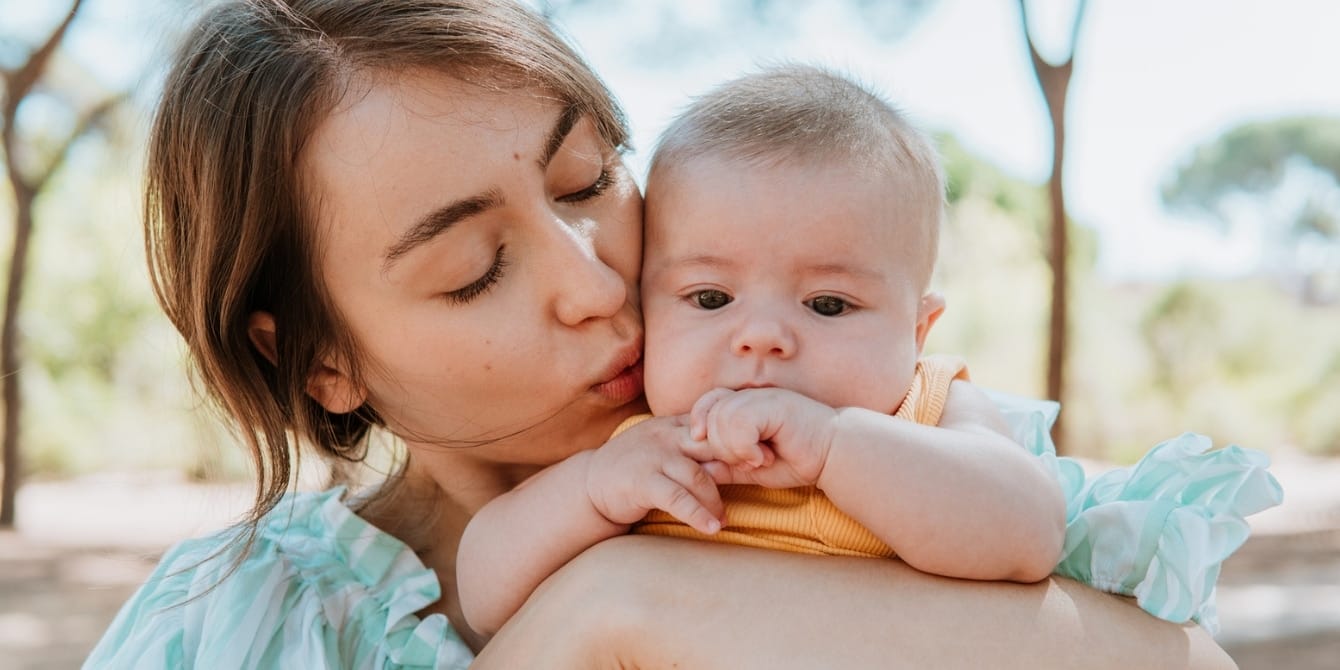 mom kissing baby boy outside - path to parenthood