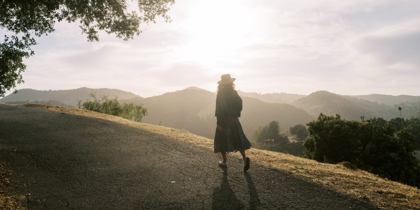 woman walking on empty road at sunset - silent walk