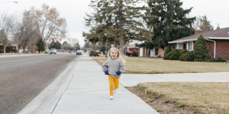 child running on neighborhood sidewalk - childhood independence