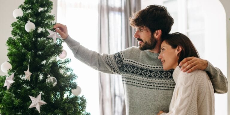 husband and wife by a christmas tree - 7 months postpartum and pregnant