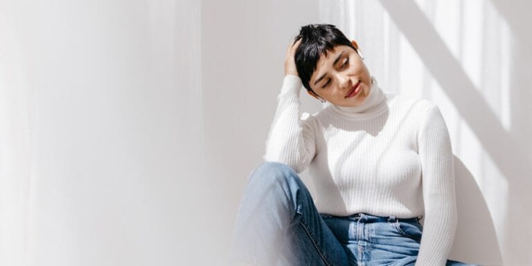 latina woman sitting on the floor at home - parental milestone anxiety