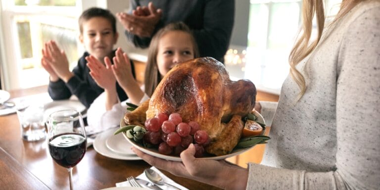 woman bringing thanksgiving turkey in to her family - thanksgiving hacks