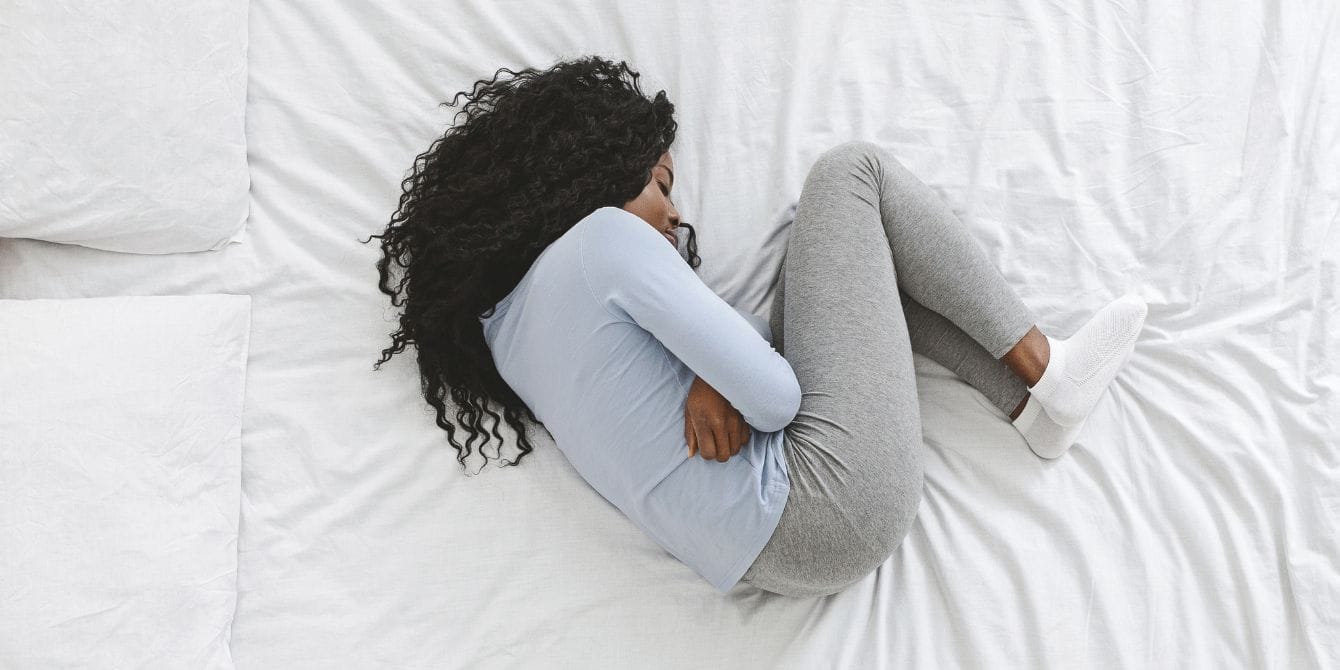 woman on the bed holding her stomach- periods cause brain changes