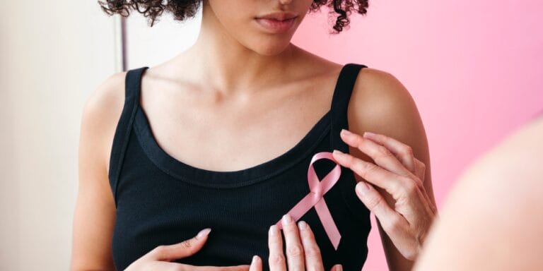 woman pinning on breast cancer awareness pink ribbon - breast cancer awareness tips