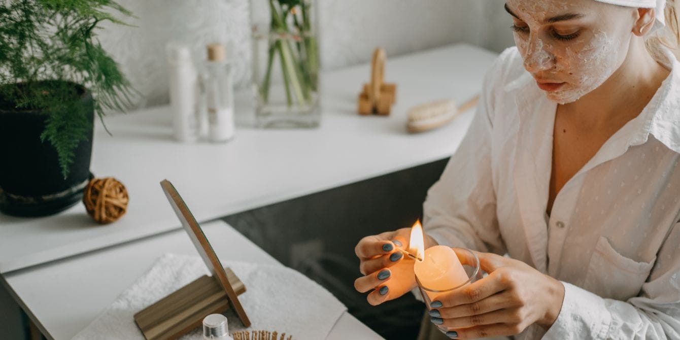 woman wearing face mask lighting a candle