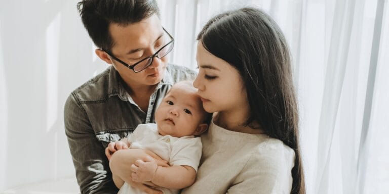 young couple holding their baby Motherly