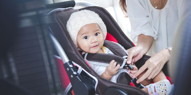 mom securing baby in car seat- winter car safety