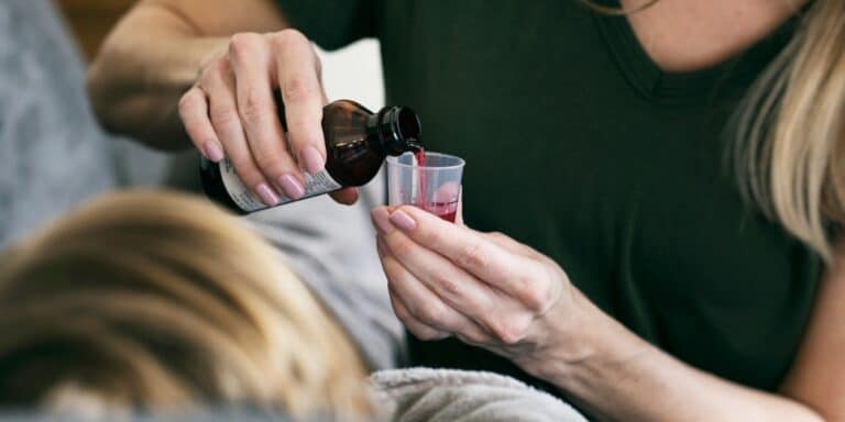 woman pouring cough syrup for her sick son - sick days