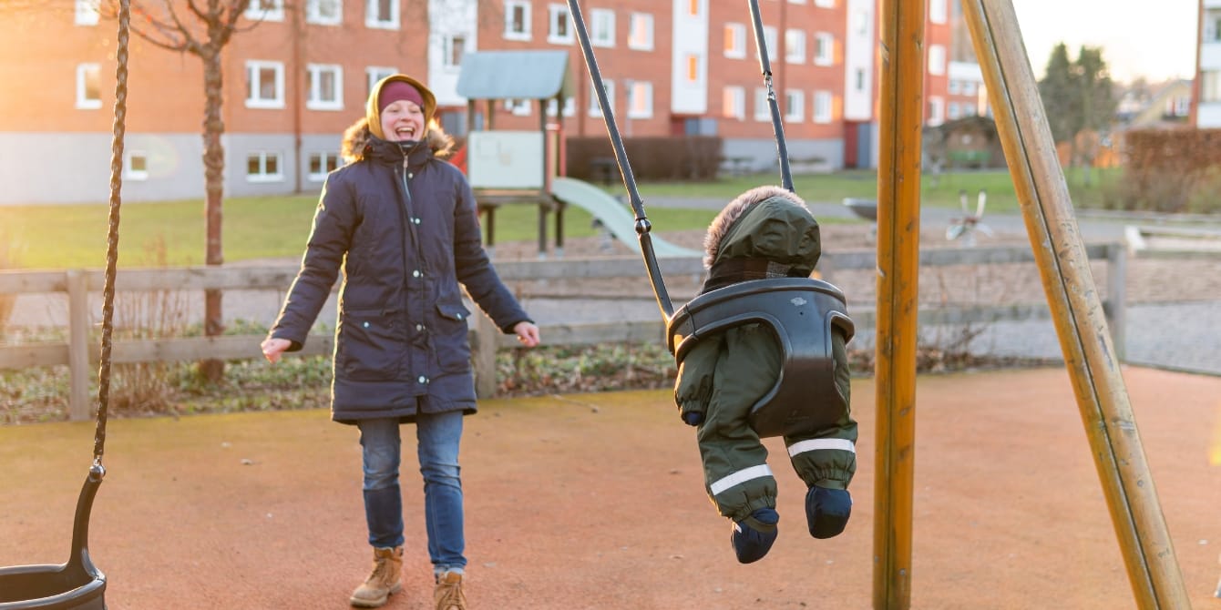 happy mom pushing toddler on swings