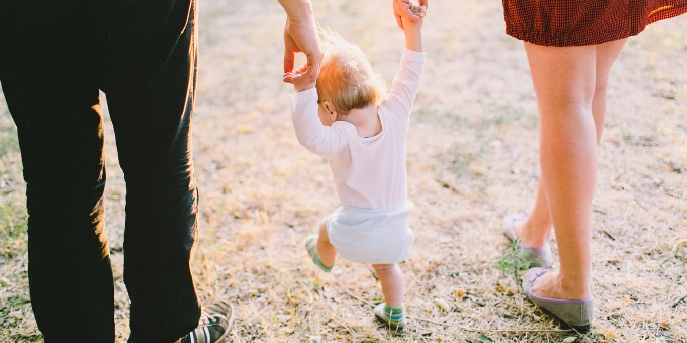 parents walking holding toddler hands