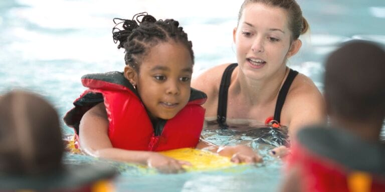 Woman giving swimming lessons to young girl