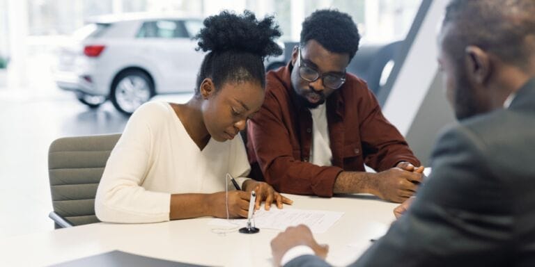 couple signing contract with car dealer buying safe family car