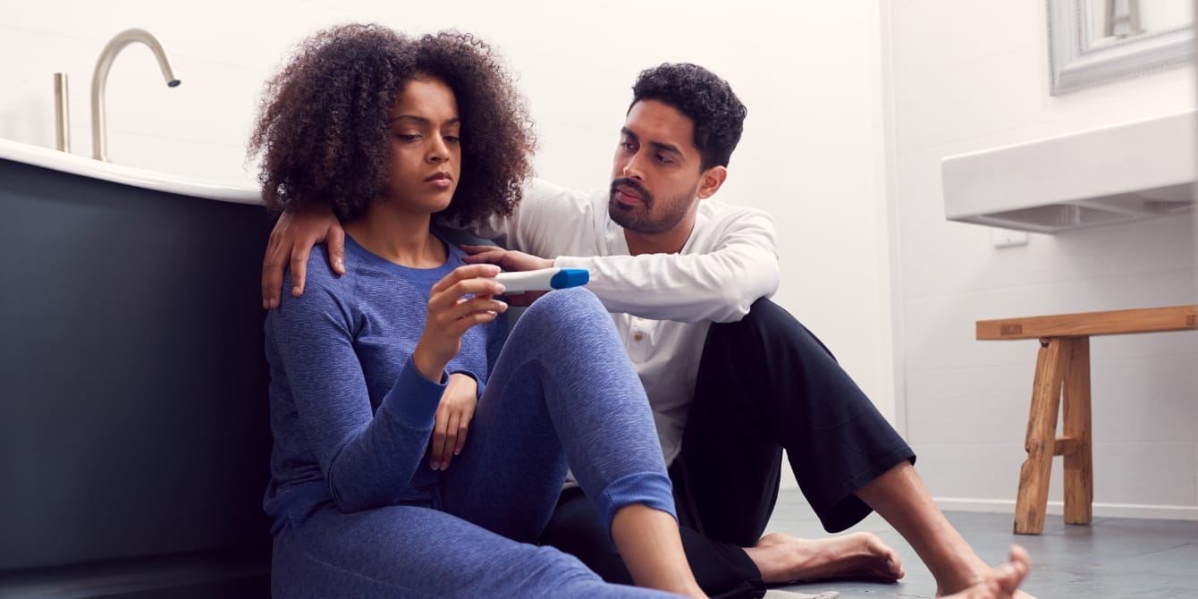 sad woman and man looking at pregnancy test