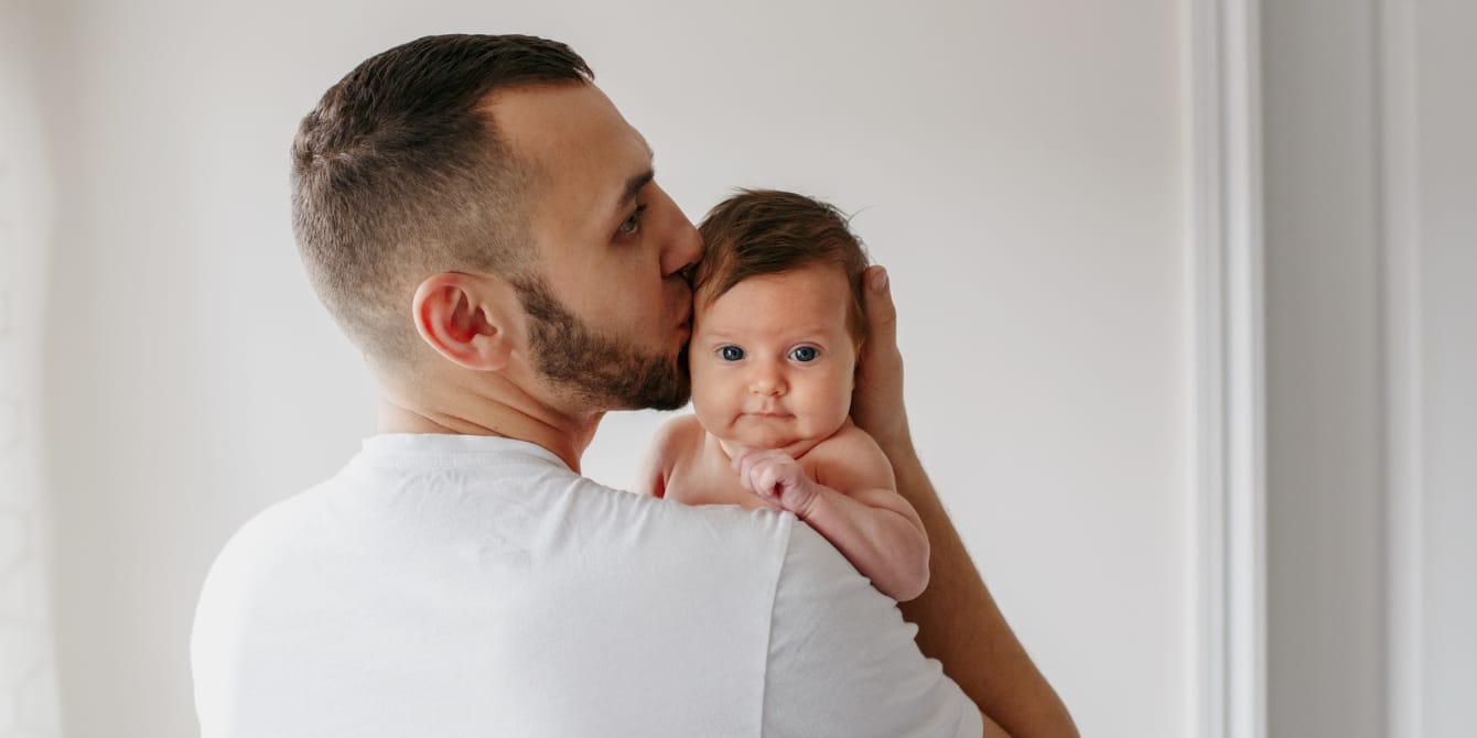 father kissing baby paternity leave