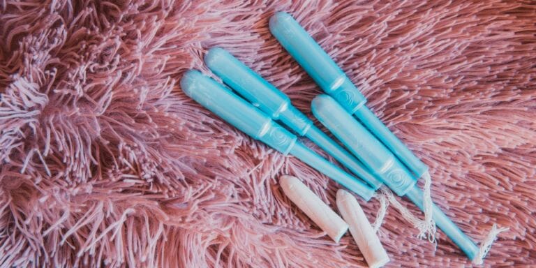 blue tampon applicators and tampons on pink shag rug