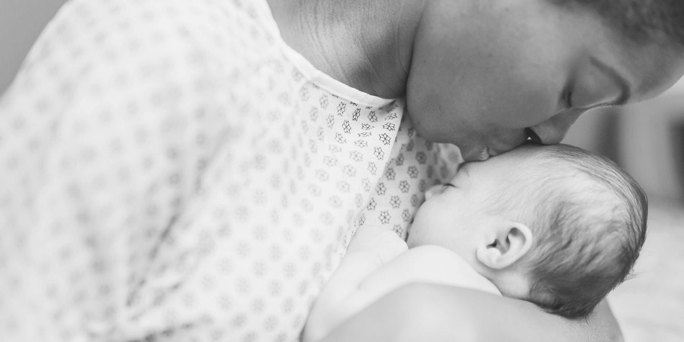 Black mother in hospital gown kissing baby