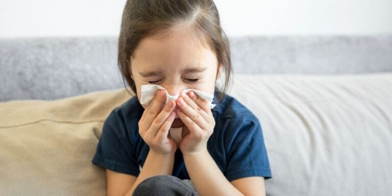 Girl sneezing into tissue