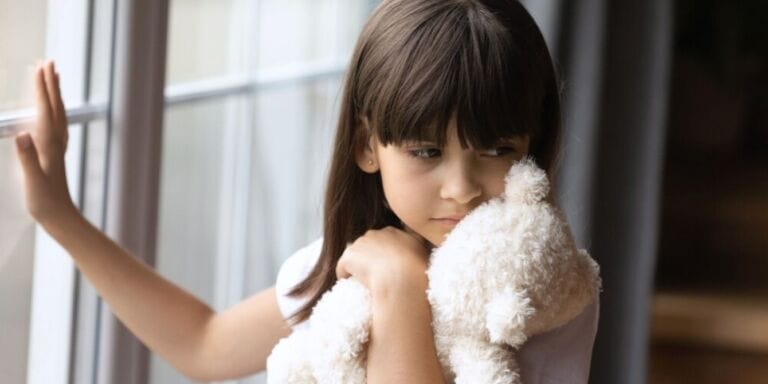 Shy little girl holding a stuffed teddy bear